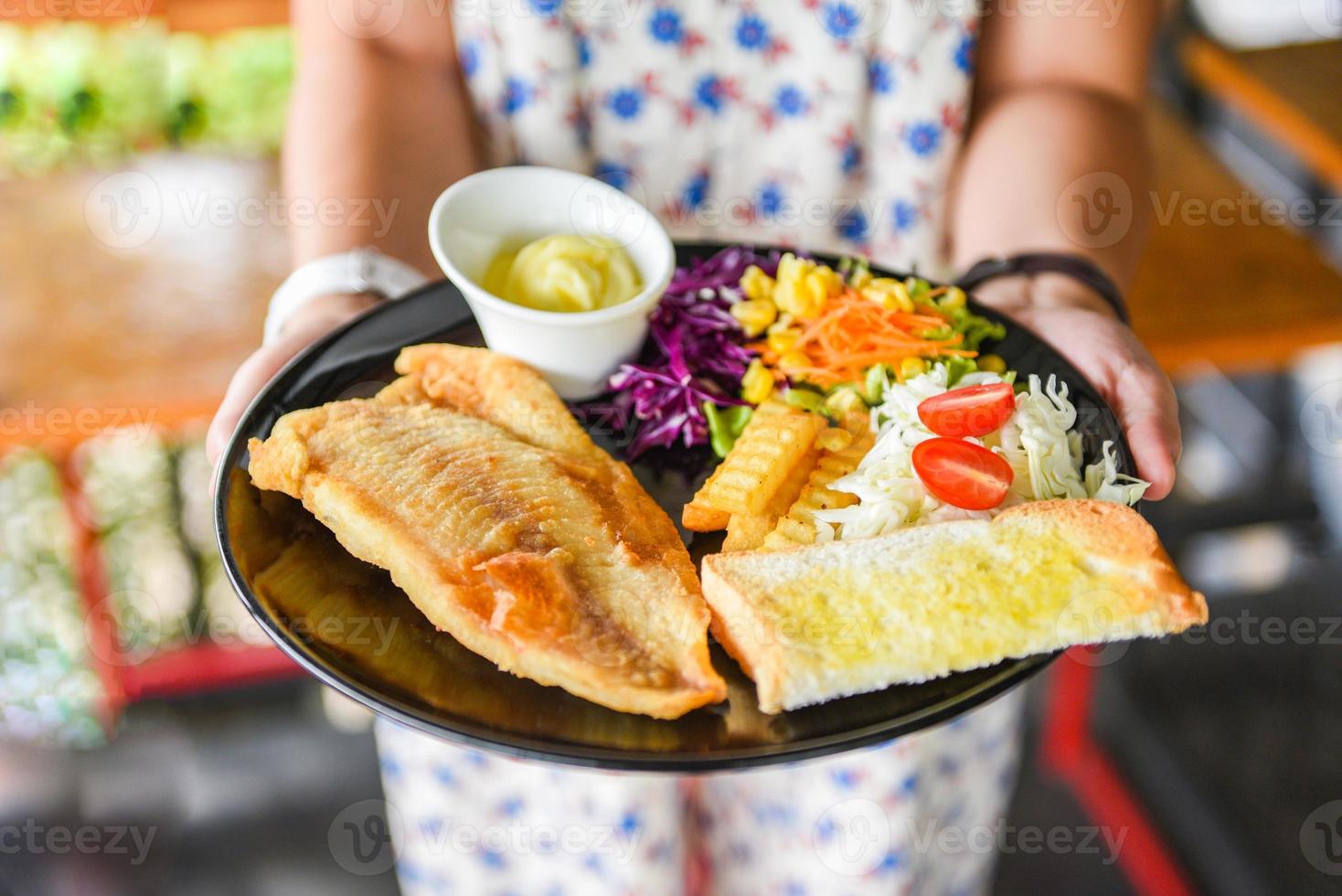 gebratenes Fischfilet Steak Fisch mit Sauce Sahne Pommes frites Brot und frisches Gemüse auf Teller serviert Fischgericht foto