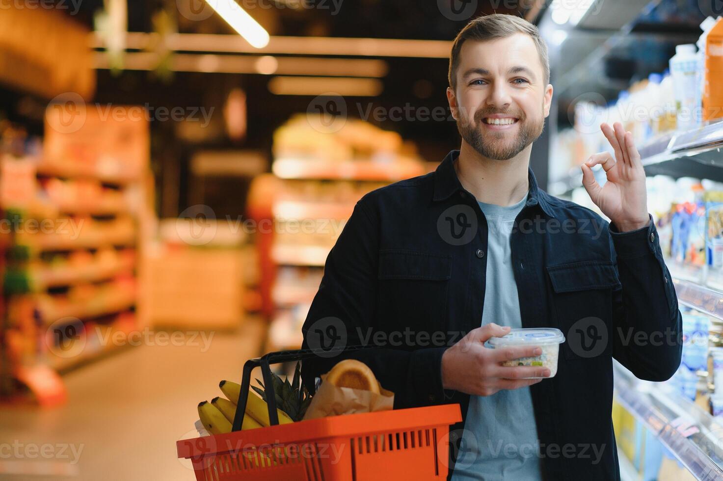 Kunde im Supermarkt. Mann tun Lebensmittelgeschäft Einkaufen Stehen mit Wagen wählen Essen Produkt drinnen. Kerl Kauf Lebensmittel im Essen speichern. selektiv Fokus, Kopieren Raum. foto