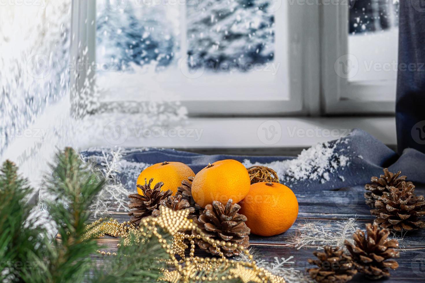 Mandarinen auf grauem Hintergrund mit Zweigen eines Weihnachtsbaumes, im Hintergrund ein Fenster mit Schnee. neues Jahr Konzept. foto