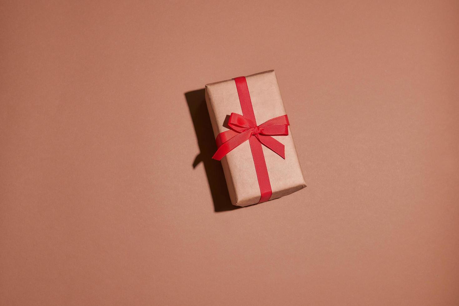 Valentinstag Zusammensetzung. Geschenk- oder Geschenkbox verpackt in Kraftpapier mit Herz auf pastellfarbenem Hintergrund foto