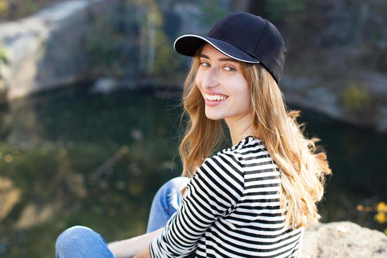 glückliche junge Frau in einem stylischen Blazer, der auf einem Hintergrund von Bergen und Wald posiert - aktives Ruhekonzept foto