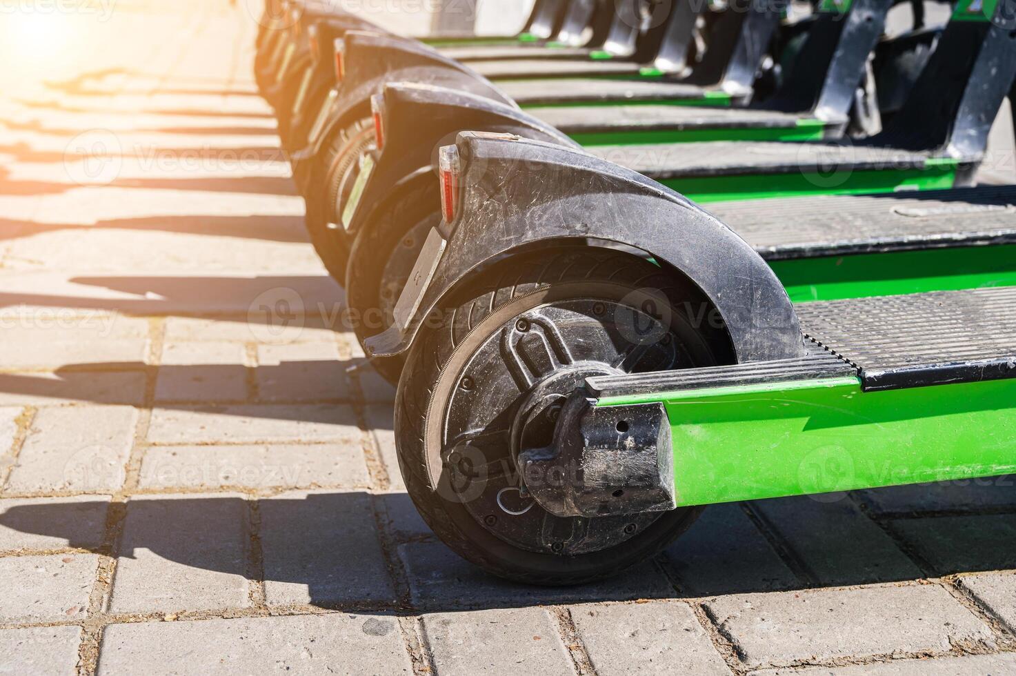 Räder von Grün elektrisch Roller Stehen im ein Reihe zum Vermietung auf Bürgersteig im Stadt im Sommer- auf sonnig Tag foto
