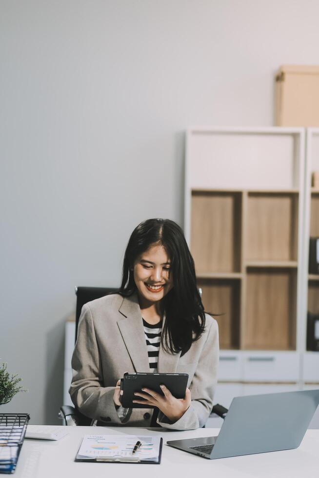 Die junge asiatische Geschäftsfrau arbeitet gerne im modernen Büro mit einem Tablet. foto