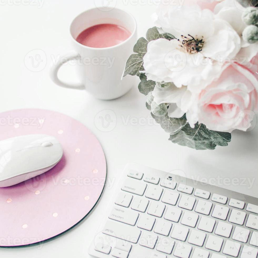 Weißer Arbeitsplatz mit hellrosa Notizbuch und weißer Blume mit Kaffee auf weißem Tisch. foto