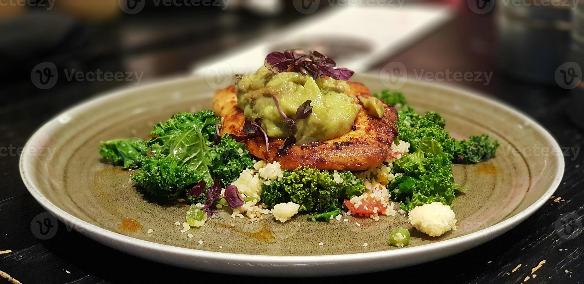 Salat mit Hühnchen und Mayonnaise-Sauce auf einem Teller auf einem Holztisch foto