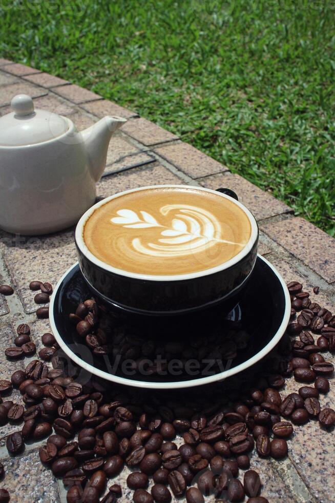 Kaffeemilch in Baumform in einer Tasse mit Kaffeebohnen darunter foto