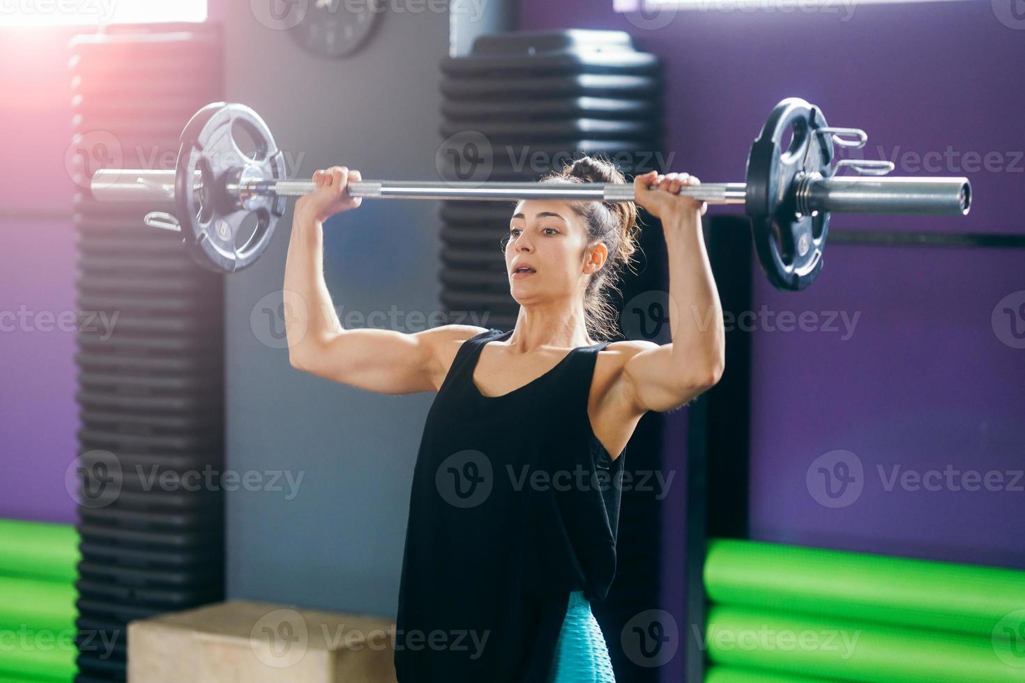 athletische Frau im Fitnessstudio, die Gewichte im Fitnessstudio hebt foto