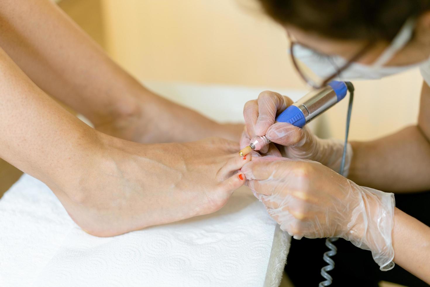 Kosmetikerin bei einer Pediküre, die die Nägel ihrer Kundin in einem Schönheitszentrum lackiert. foto