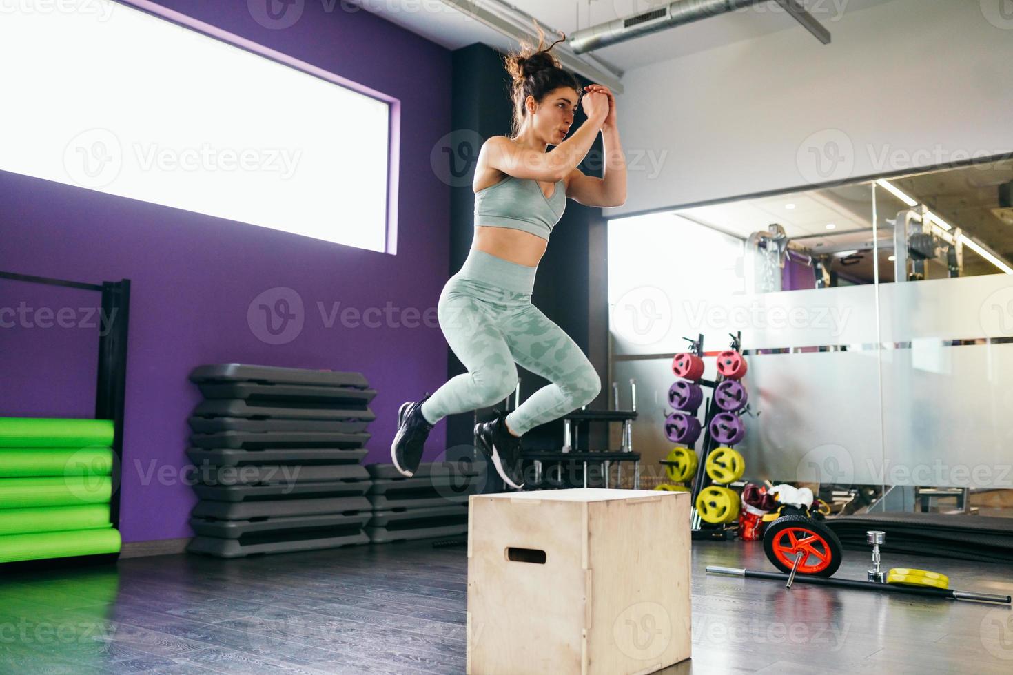 Fitness-Frau, die im Rahmen der Trainingsroutine auf eine Kiste springt. foto