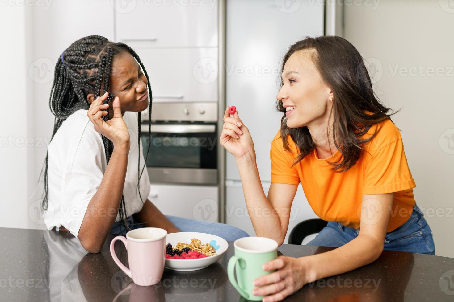 zwei Freunde, die zu Hause einen gesunden Snack essen, während sie sich unterhalten foto