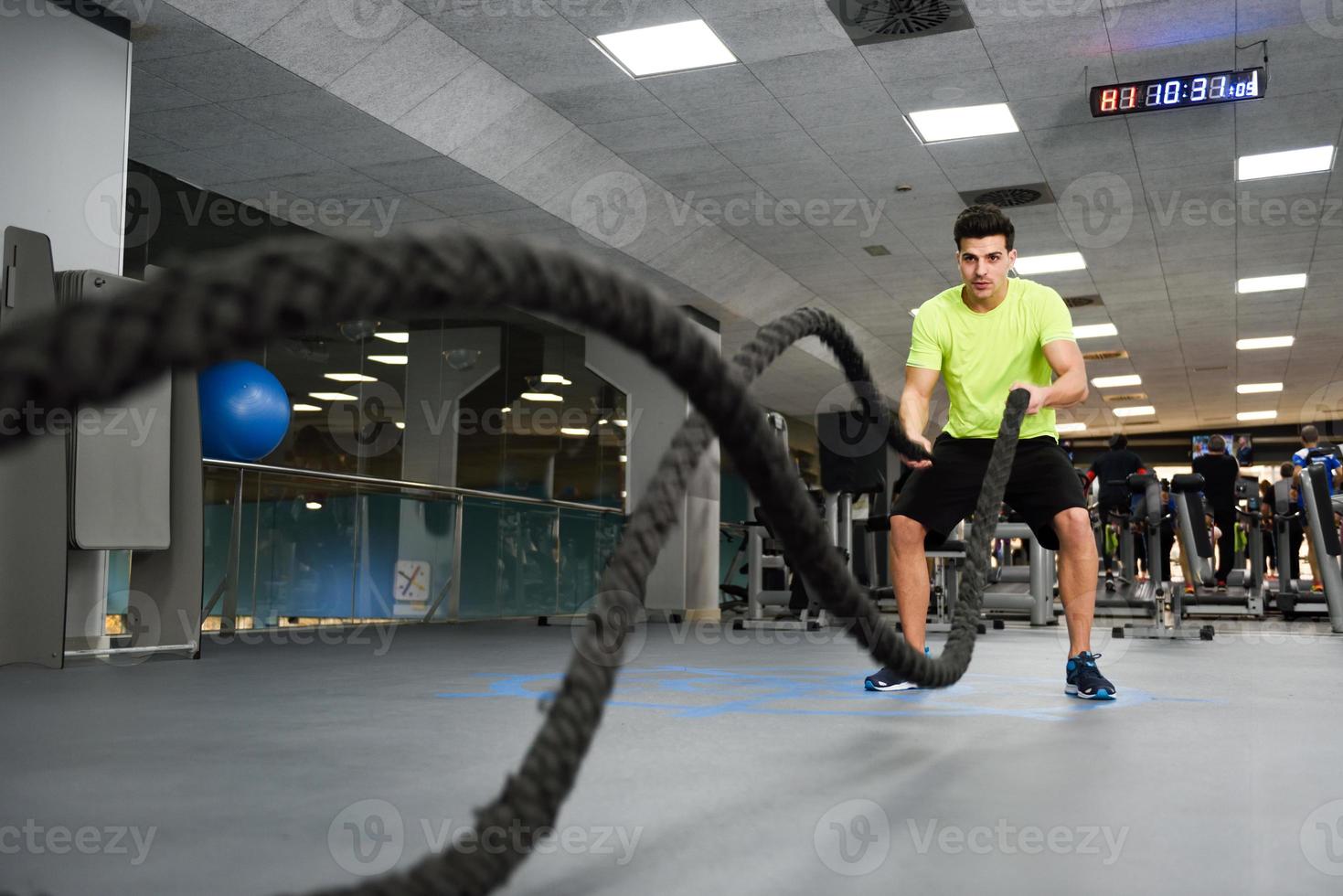 Mann mit Kampfseilen trainiert im Fitnessstudio. foto