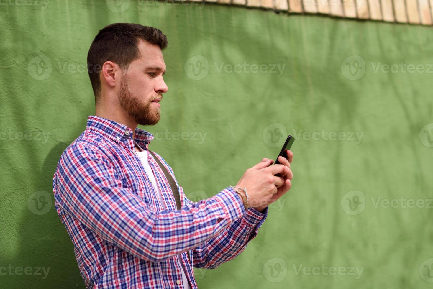 junger Mann, der sein Smartphone im städtischen Hintergrund betrachtet. Lifestyle-Konzept. foto