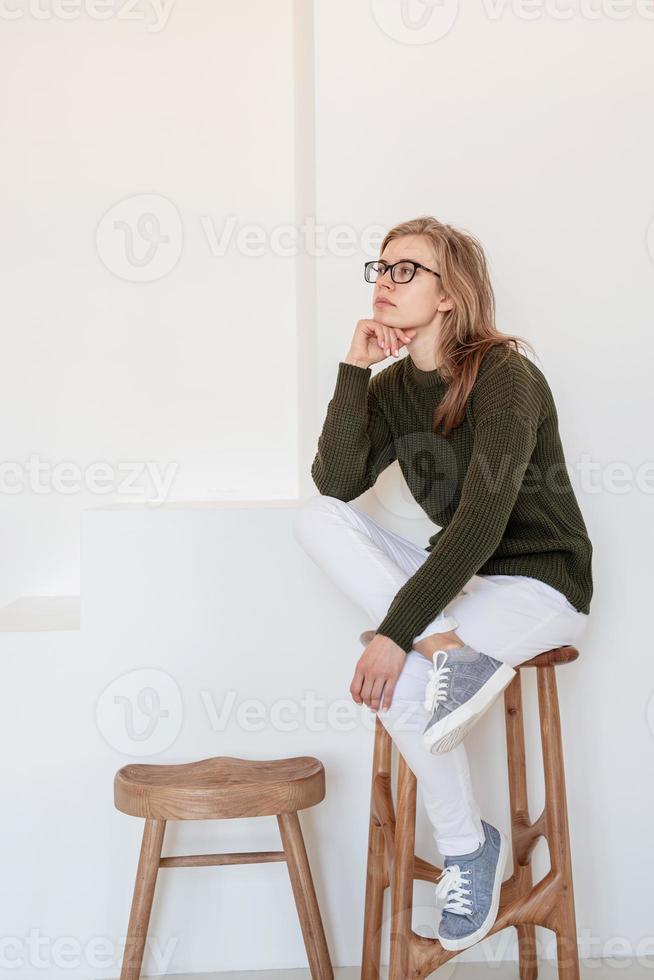 attraktive junge Frau, die auf dem Stuhl in hellem und luftigem Innenraum sitzt foto