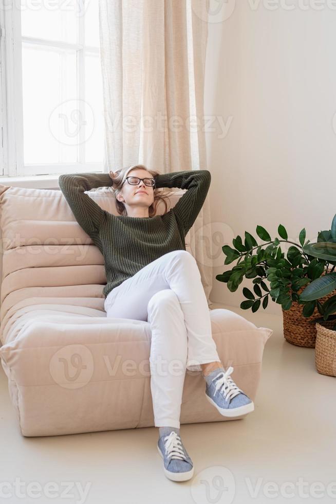 attraktive junge Frau sitzt auf dem Stuhl in hellem und luftigem Interieur mit Pflanzen foto