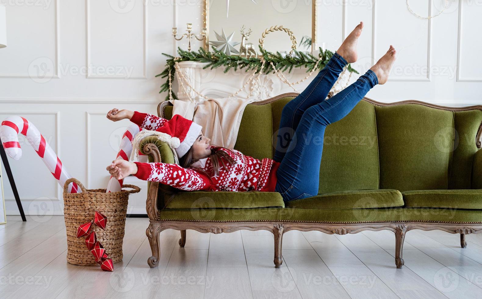 junge Frau liegt allein auf der Couch in einem weihnachtlich dekorierten Wohnzimmer foto