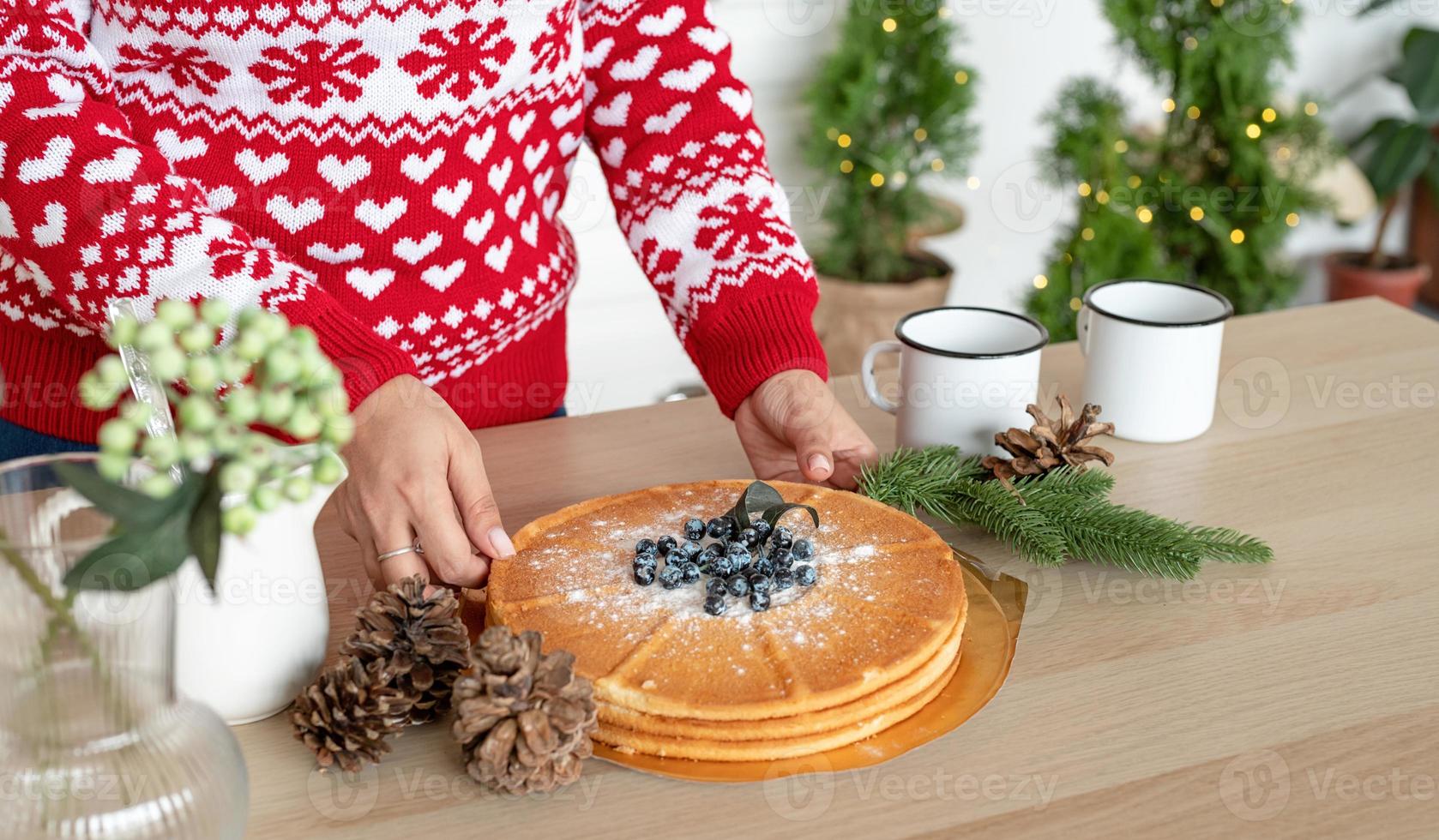 glückliche junge Frau im Weihnachtspullover, die heiße Getränke in der Küche macht foto