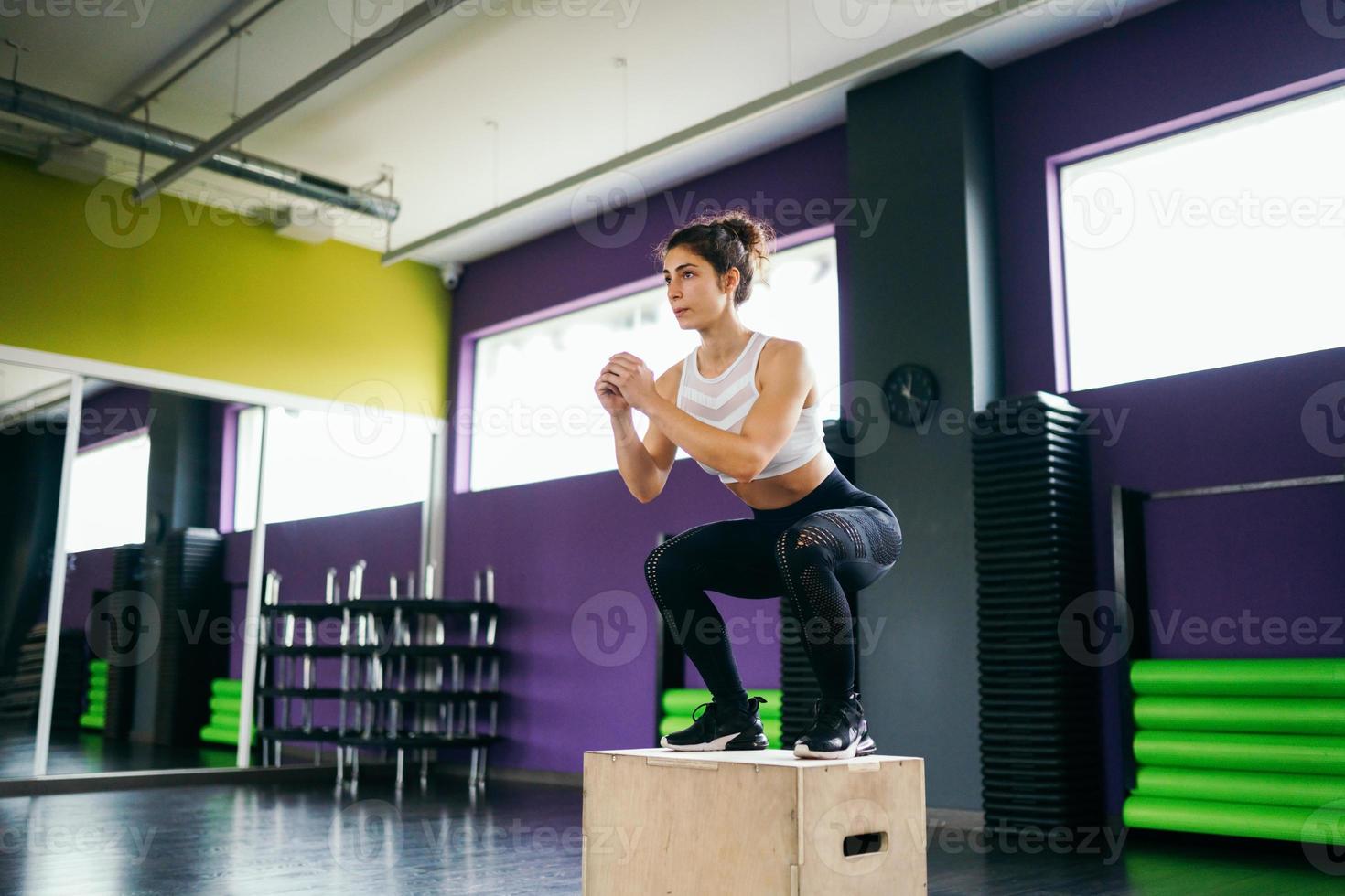 athletische Frau macht Kniebeugen auf Box im Fitnessstudio foto