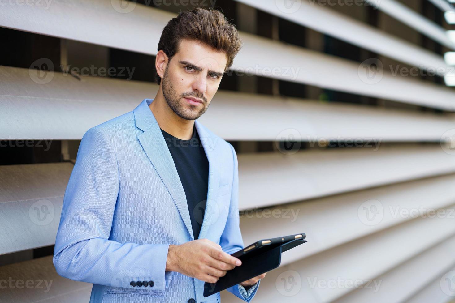 Geschäftsmann mit einem digitalen Tablet in der Nähe eines Bürogebäudes foto