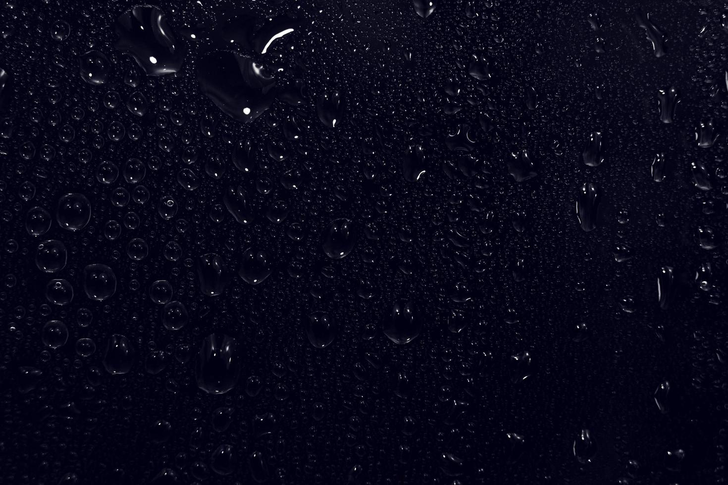 Wassertropfen auf schwarzem Hintergrund. abstrakte Tauwassertröpfchen auf einem Fensterglas für einen Foto-Overlay-Effekt oder einen frischen Effekt auf ein Getränkemodell. Makroaufnahme des detaillierten Regentropfens. foto