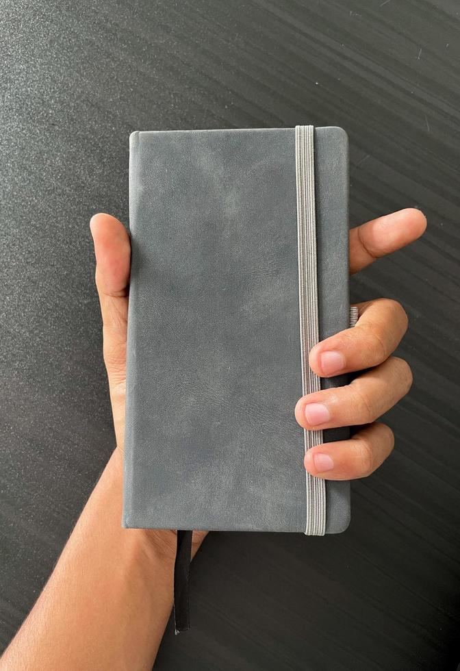 Notizbuch in der Hand. ein kleines graues Notizbuch, um alles festzuhalten, auch Ideen und wesentliche Dinge. geschlossenes Notizbuch mit Trennwand. foto