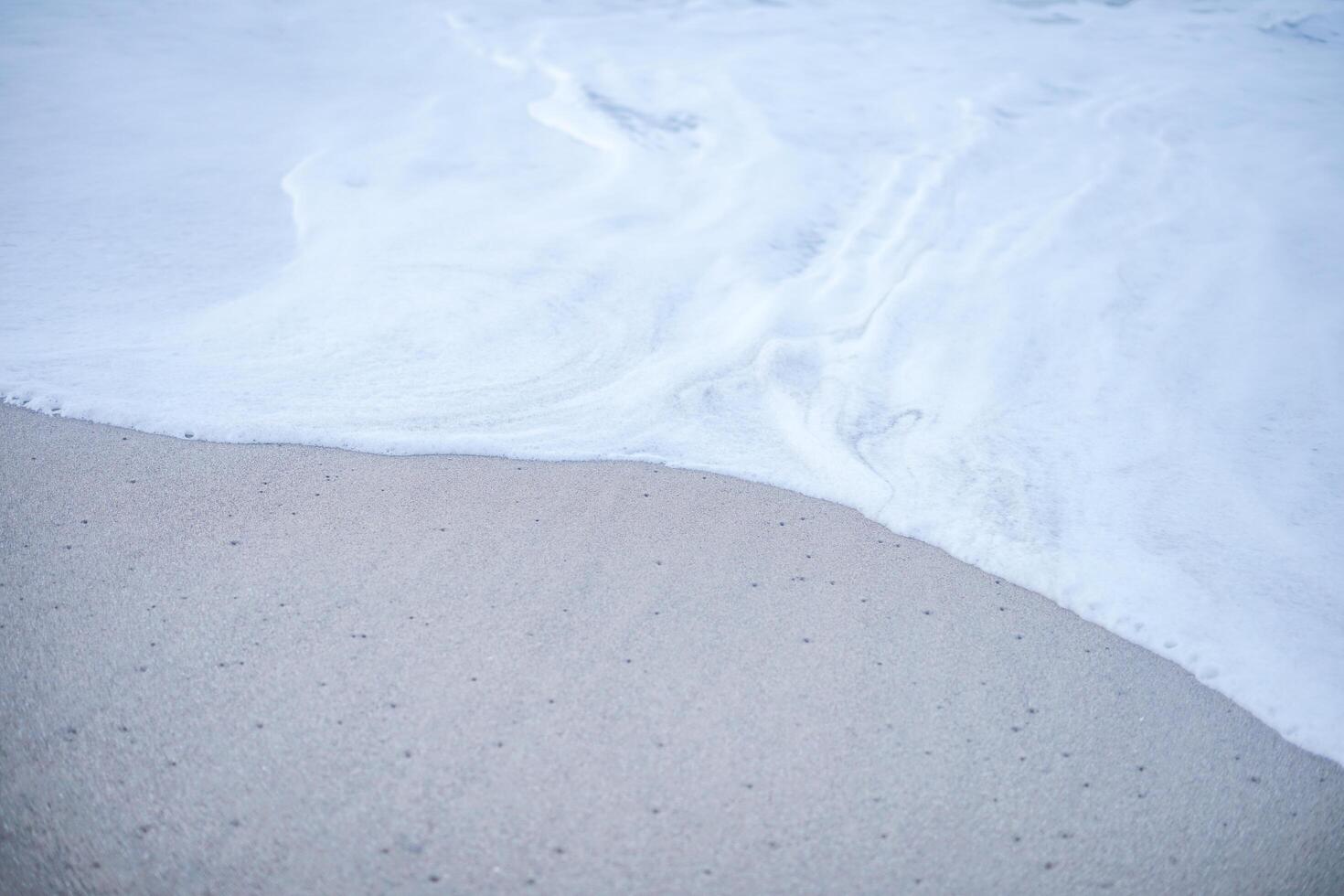 die Schaumwelle am Sandstrand. sanfte Wellen an der Küste, die sich ruhig und angenehm zum Entspannen anfühlen. foto