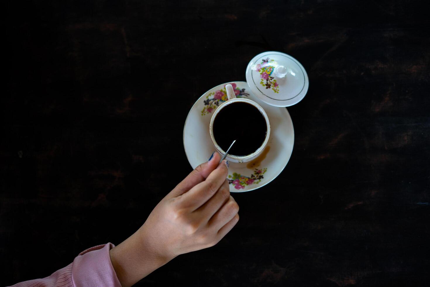 Auf dem Tisch steht eine Tasse heißen Kaffee. Ein Mädchen hält ein leckeres Getränk in der Hand. eine Art Freizeitvergnügen. foto