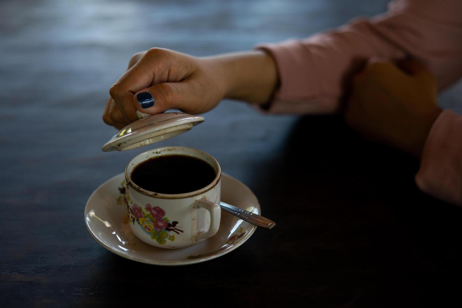 Auf dem Tisch steht eine Tasse heißen Kaffee. Ein Mädchen hält ein leckeres Getränk in der Hand. eine Art Freizeitvergnügen. foto