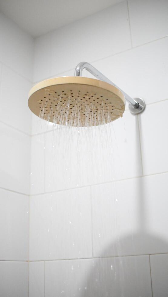 das Strahlwasser aus dem Wasserhahn der Kopfbrause. das ästhetische Badezimmer, das Wasser gießt. minimalistisches Interieur zur Veranschaulichung der häuslichen Wassernutzung. foto