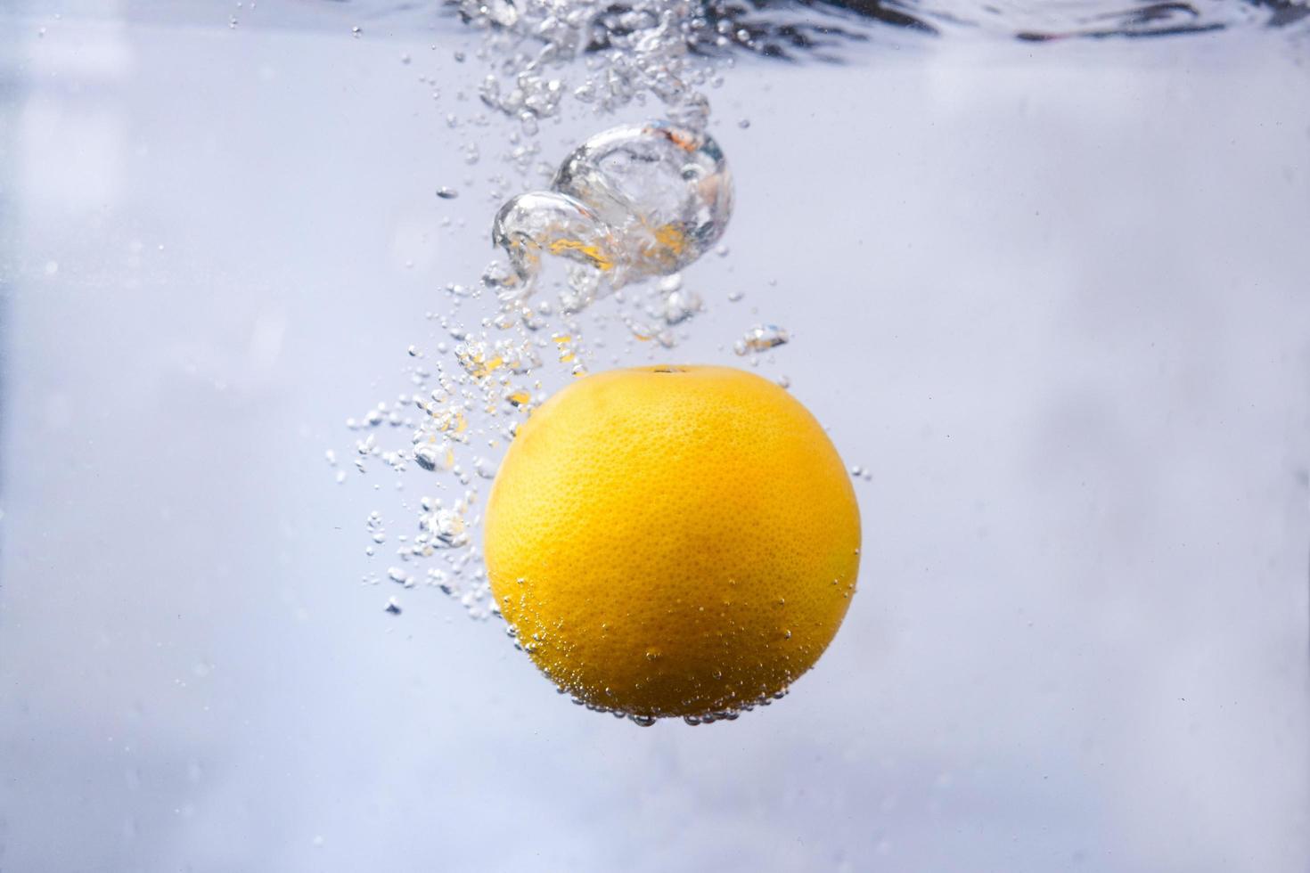eine Orange fiel in Süßwasser. Spritzwasser mit einer Orange für eine frische Naturhintergrundsammlung. foto