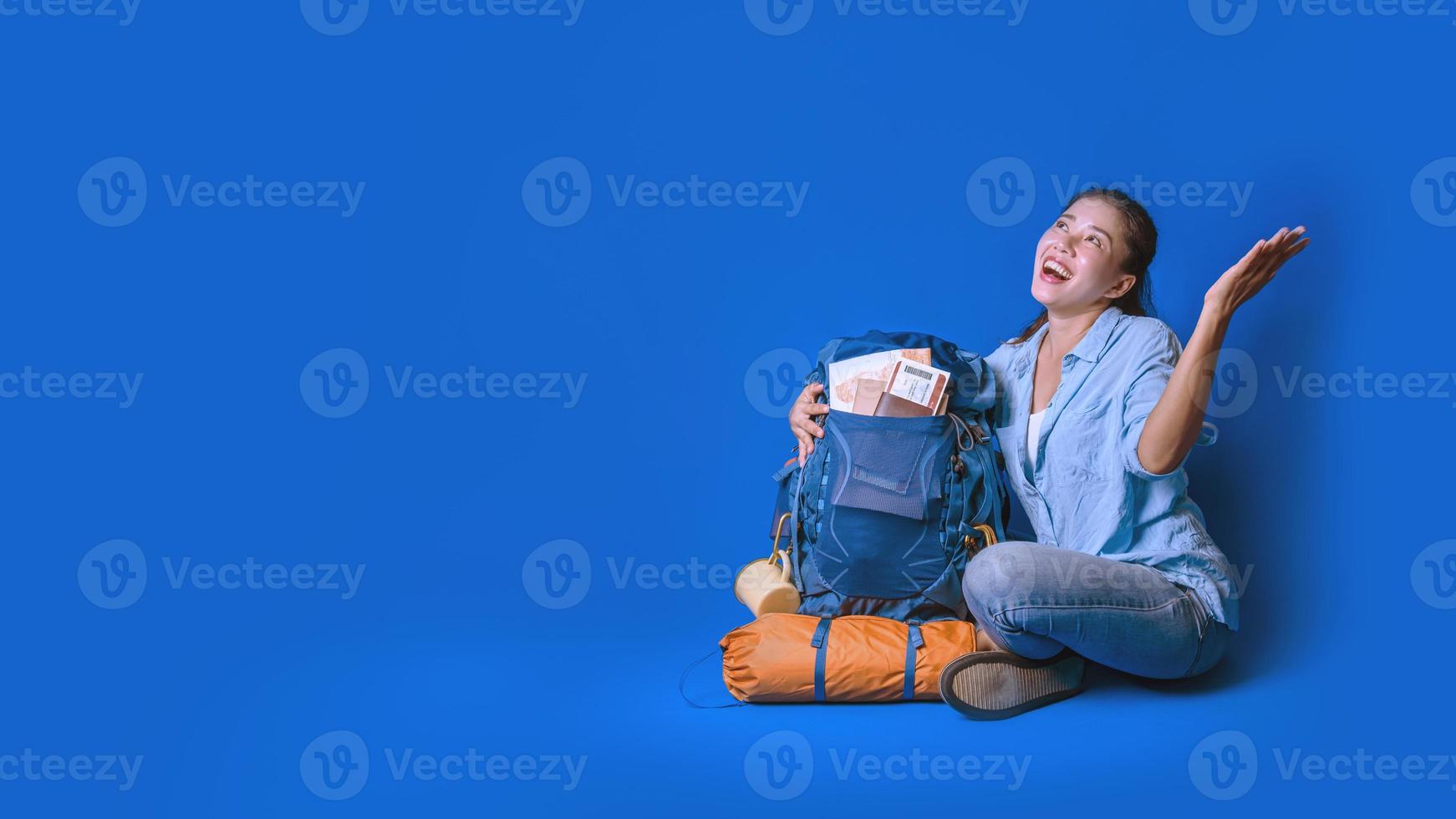 junge asiatische reisende glückliche frau im blauen hemd mit rucksack mit und ausrüstung für reisende urlaub mit einer karte, auf blauem farbhintergrund. Reiserucksack foto