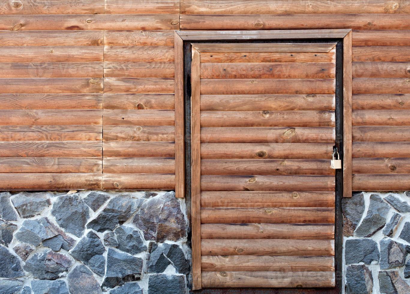 Holztür zum Hauswirtschaftsraum eines Hauses, das auf einem Steinfundament steht foto