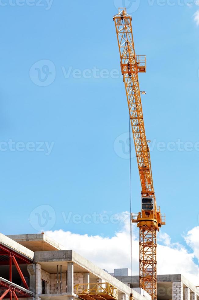 der Ausleger eines Turmdrehkrans arbeitet über einer Baustelle gegen den blauen Himmel. foto