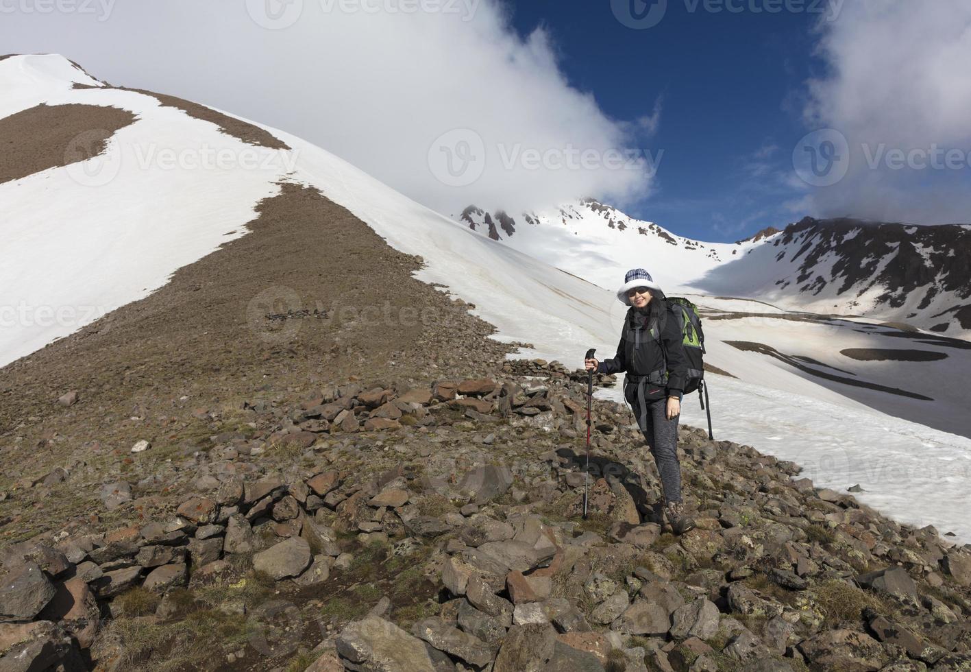 der Tourist steigt den Berghang hinauf zum schneebedeckten Gipfel foto