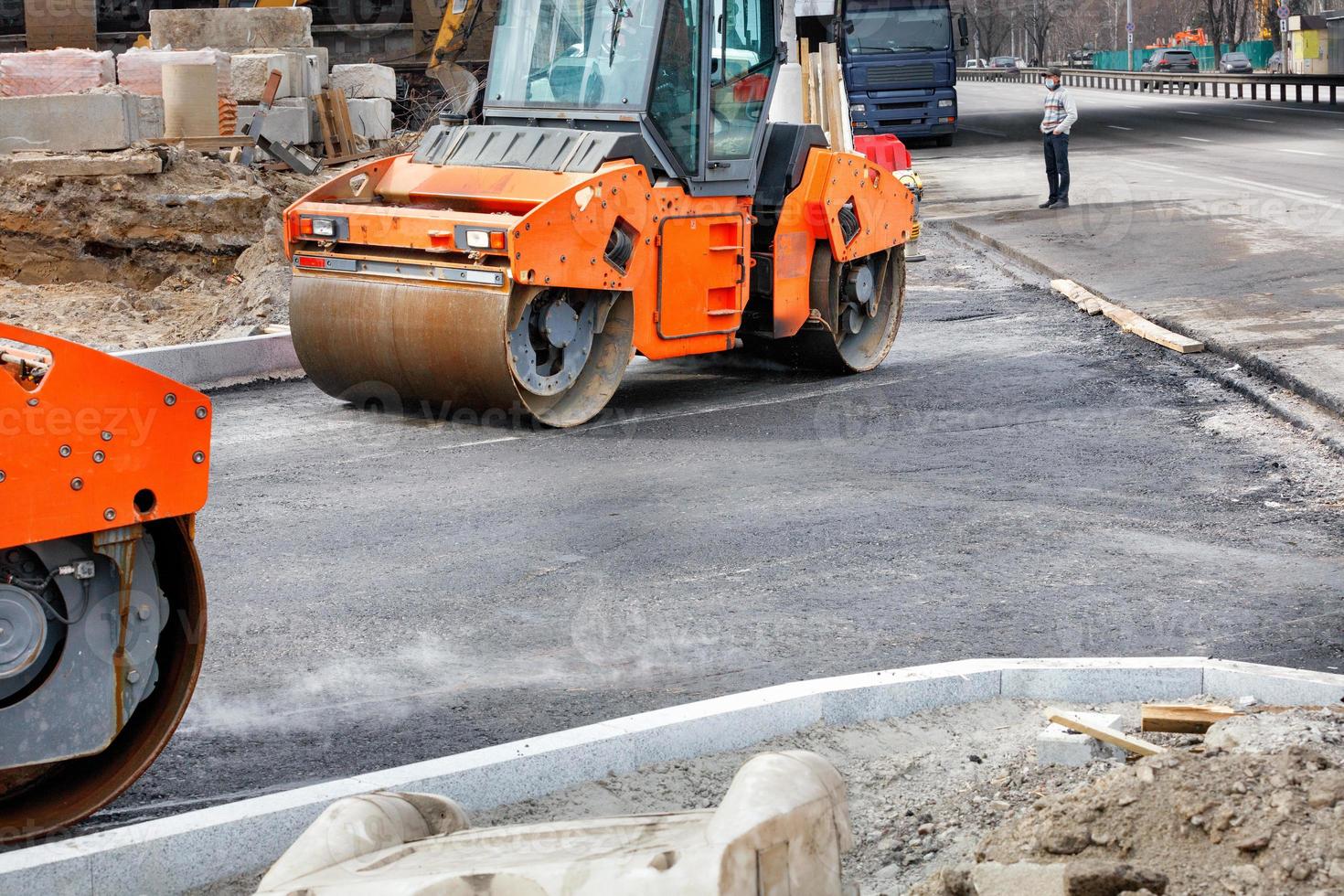 Zwei große Vibrationswalzen arbeiten auf einer Baustelle und verdichten frischen Asphalt. foto