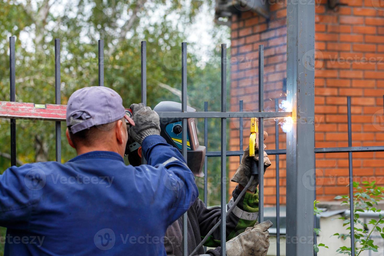 Ein Team von Bauarbeitern installiert einen Metallzaun um ein neues Zuhause. foto