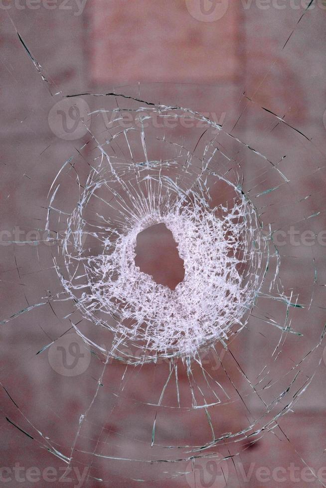 Einschussloch im Glas auf blutrotem Hintergrund. foto