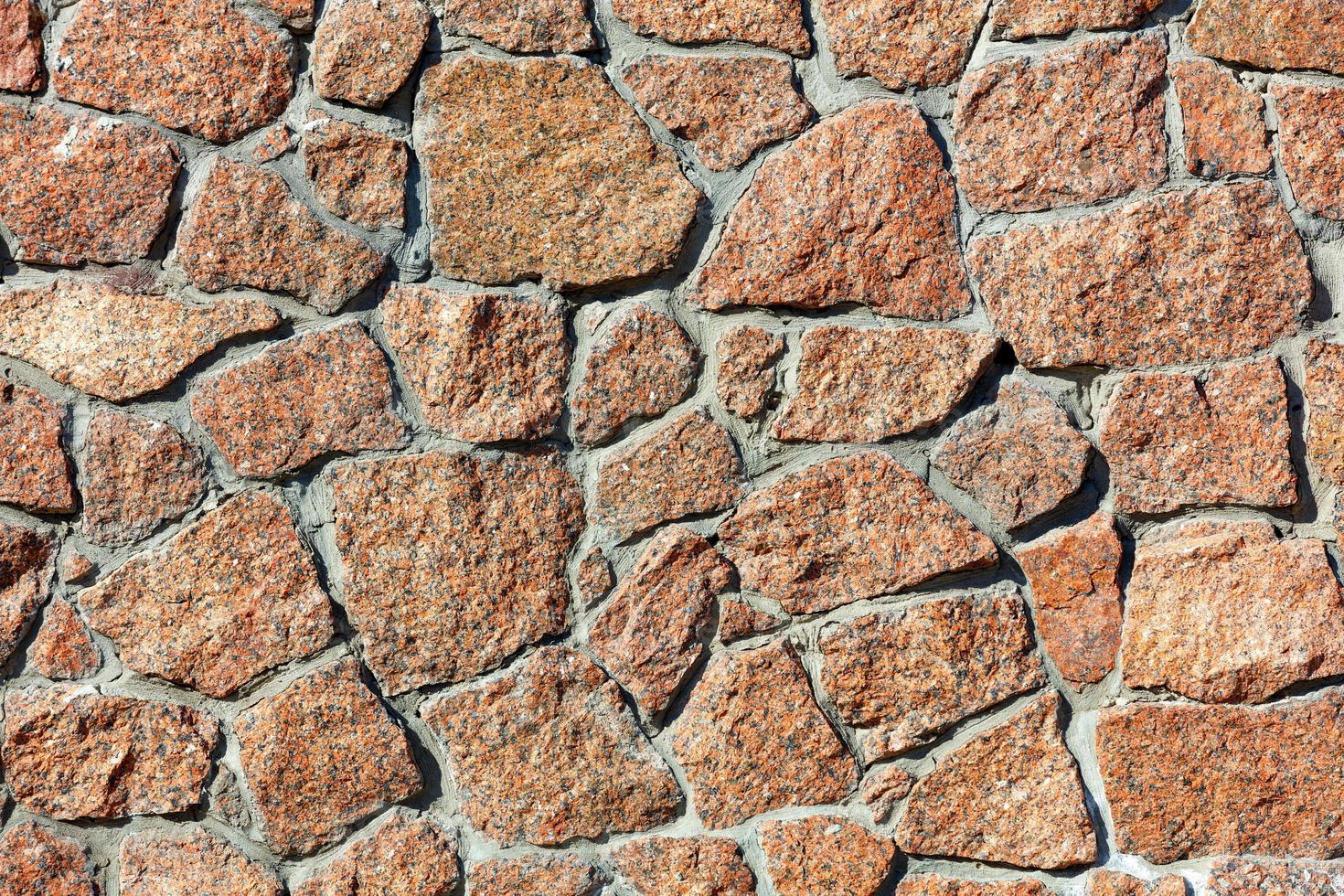 die Textur eines mit roten Granitfelsen gesäumten Zauns im Licht des Sonnenlichts. foto