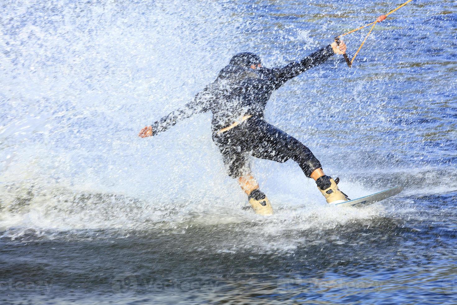 Wakeboarder rauscht mit hoher Geschwindigkeit durch das Wasser foto