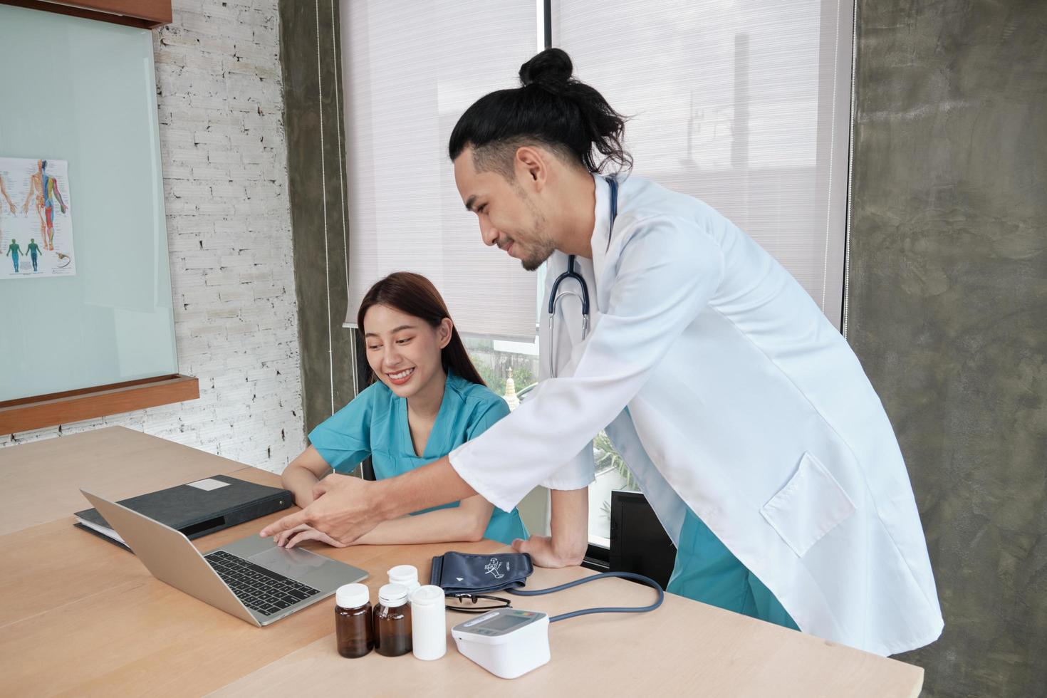 Partner des Gesundheitsteams. Zwei uniformierte junge Ärzte asiatischer Abstammung diskutieren im Büro des Krankenhauses über Medikamente. Fachpersonen sind Experten und Fachleute. foto