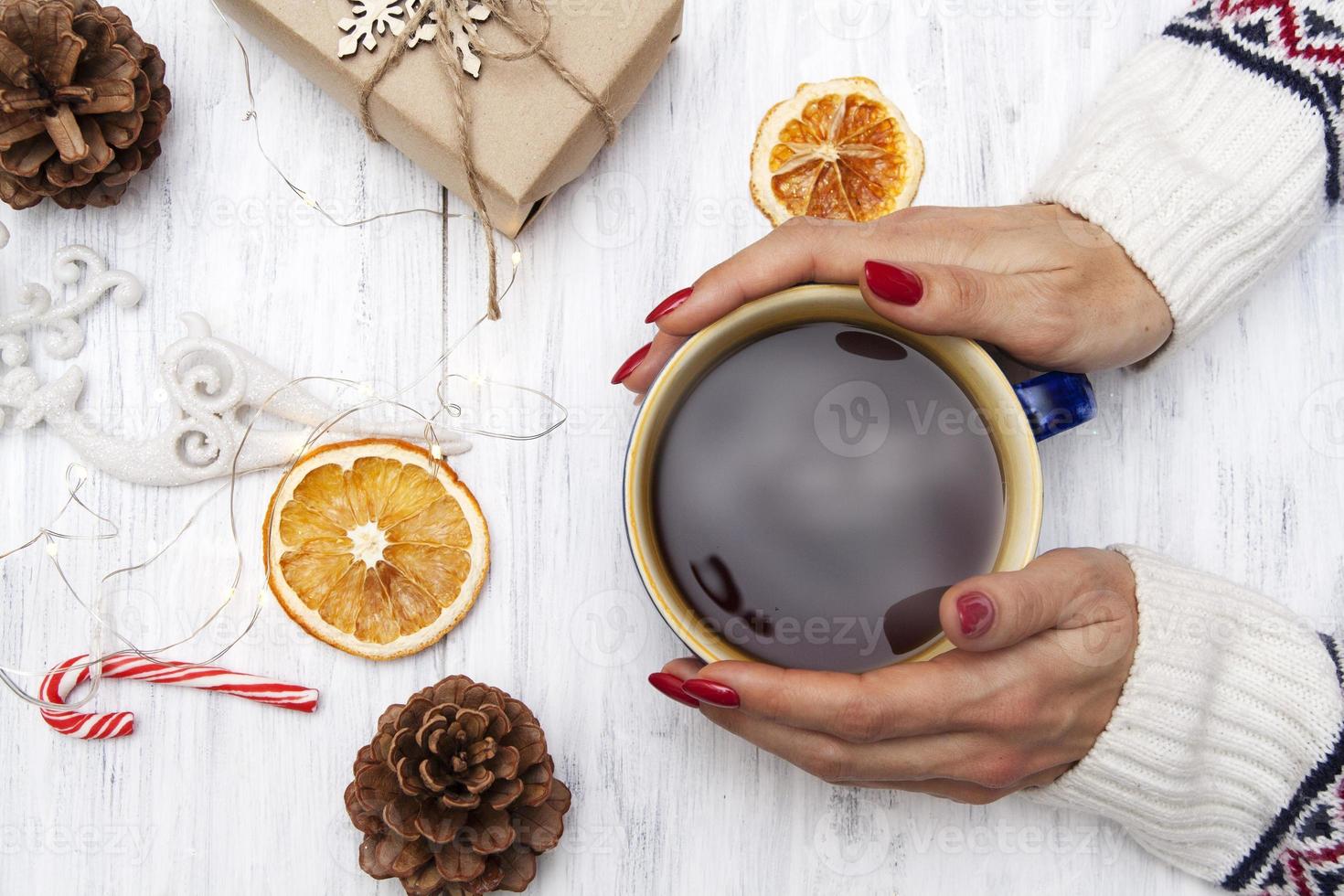 eine tasse getränk in den händen eines mädchens in einem pullover. gemütliche Winterstimmung. winter flach liegen foto