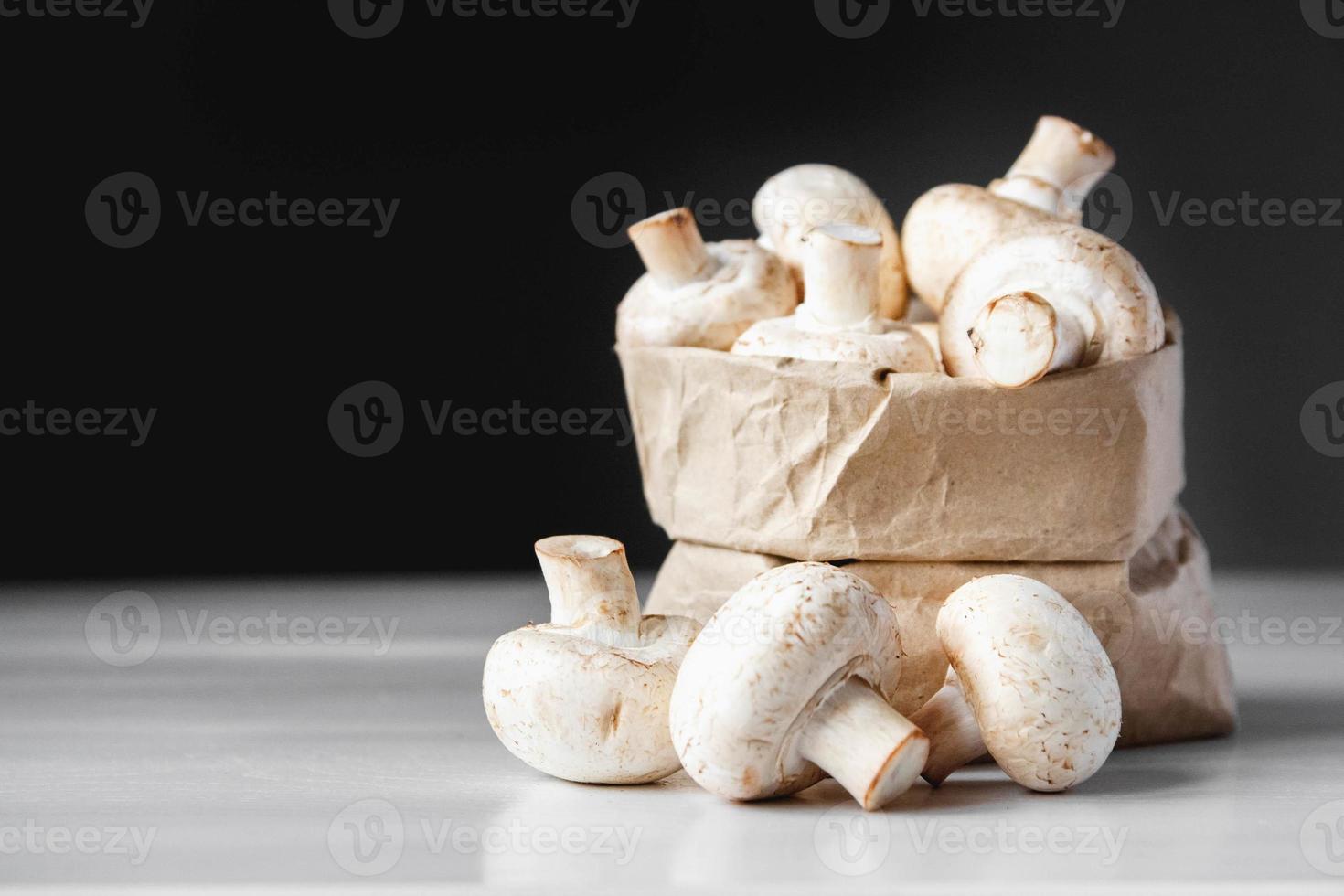 Champignons Champignons in Papiertüte auf einem weißen Holztisch auf dunklem Hintergrund foto