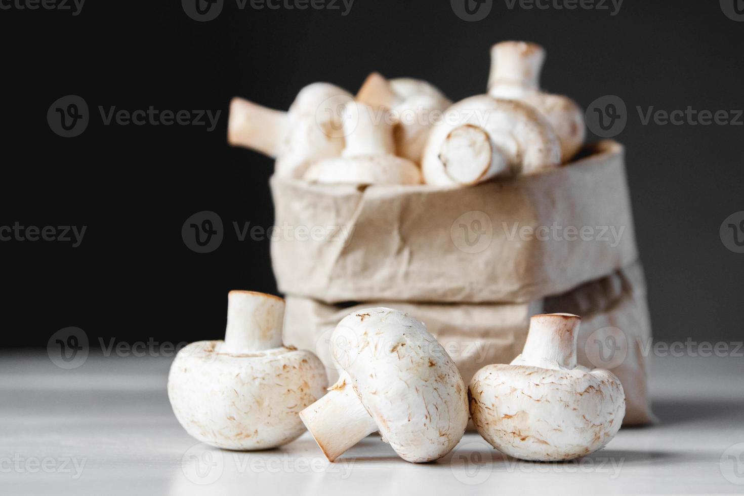 Champignons Champignons in Papiertüte auf einem weißen Holztisch auf dunklem Hintergrund foto