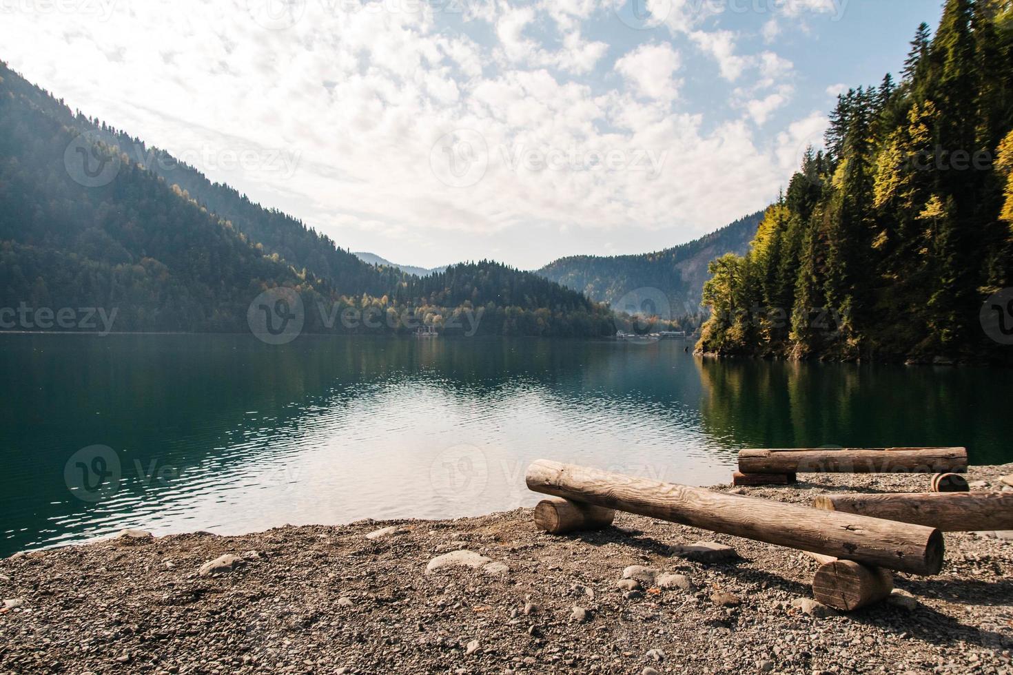 Baumstamm abgeschnitten am See auf einem Hintergrund von Bergen und Wald foto