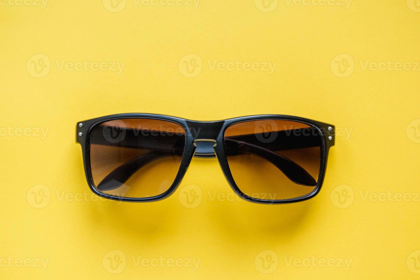 Sonnenbrille in schwarzem Rahmen auf gelbem Grund foto