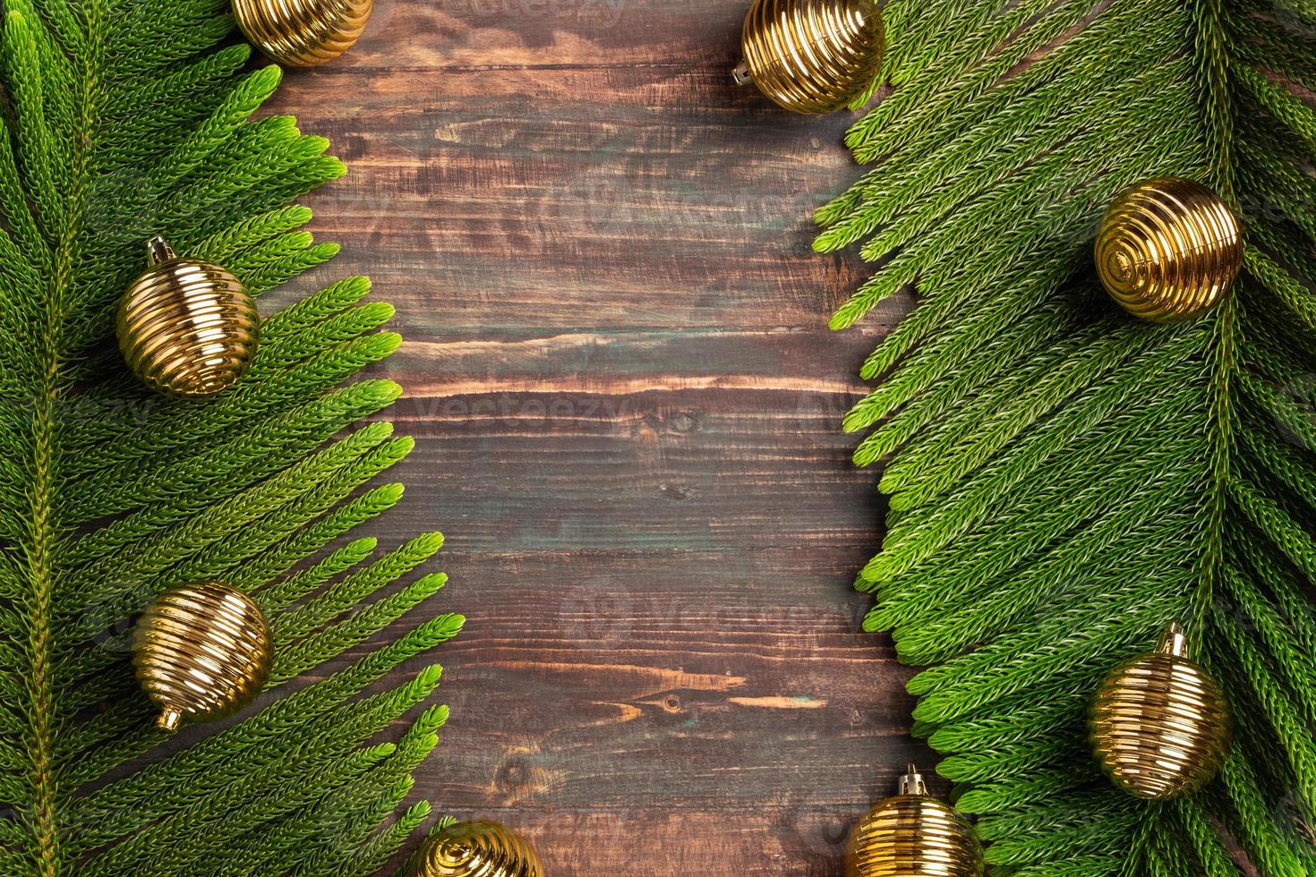 weihnachtskiefernblatt mit goldener kugeldekoration auf holztisch foto