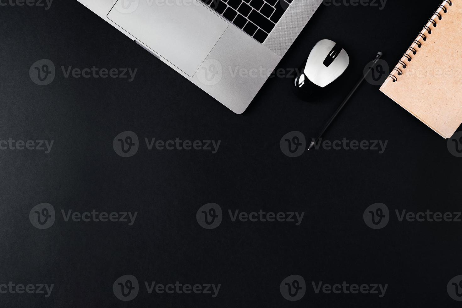 Laptop, Computermaus und Notizblock auf schwarzem Hintergrund. foto