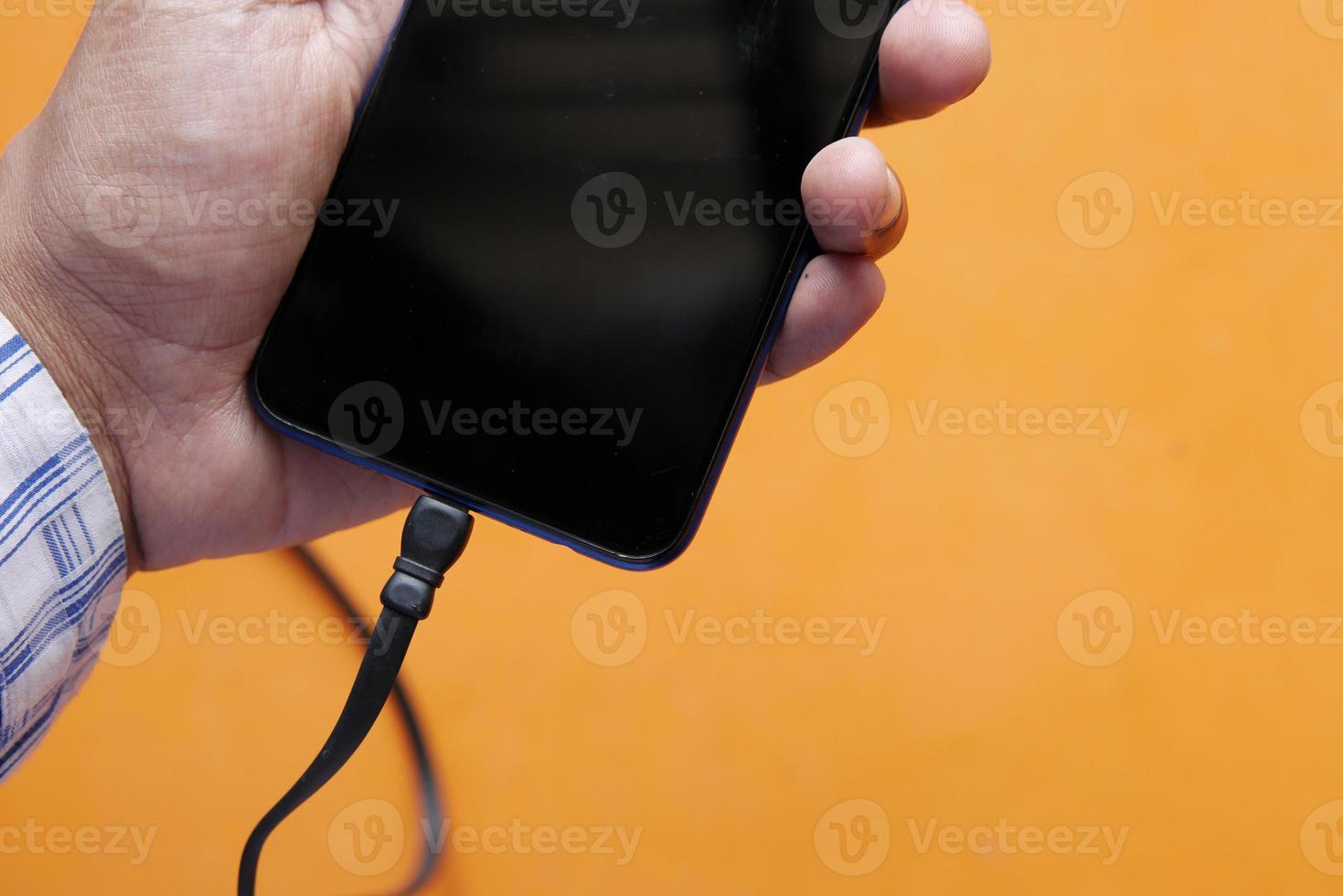 Aufladen des Smartphones mit einem Kabel auf farbigem Hintergrund foto