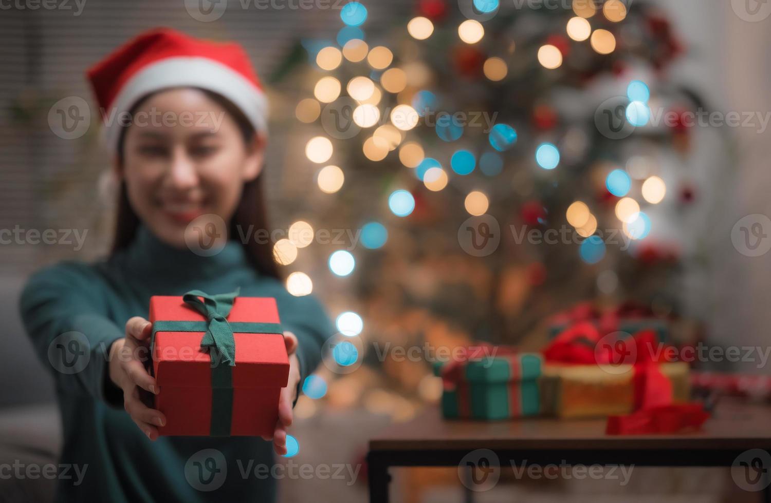 Frau mit Weihnachtsmann-Hut zeigt Geschenkbox foto