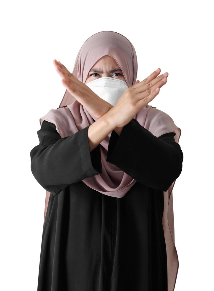 Junge muslimische Frau, die verschränkte Arme auf weißem Hintergrund zeigt, Missbilligungskonzept foto