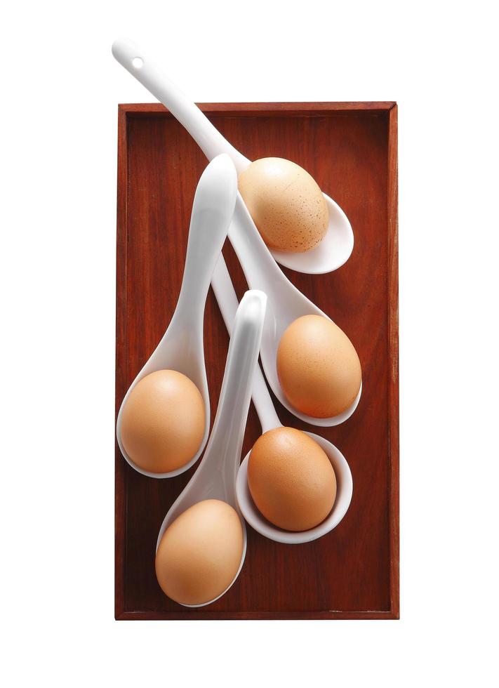 gekochtes Ei in Keramiklöffel auf weißem Hintergrund foto